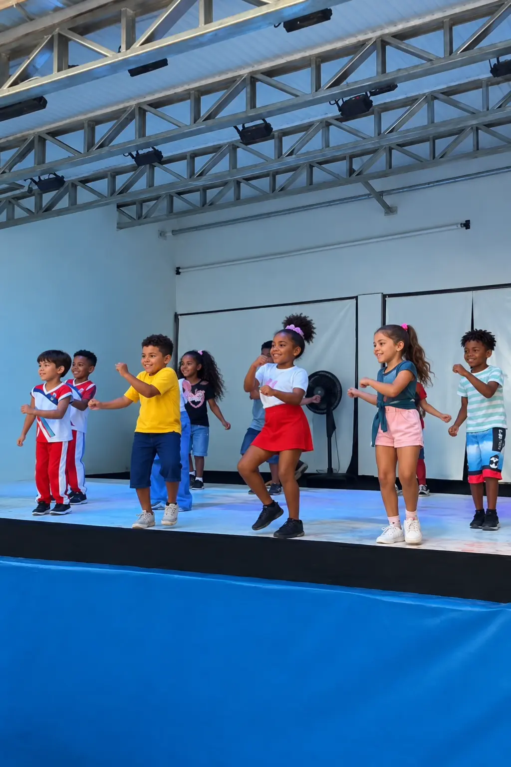 Crianças da Escola Tom e Jerry dançando em apresentação no palco da escola